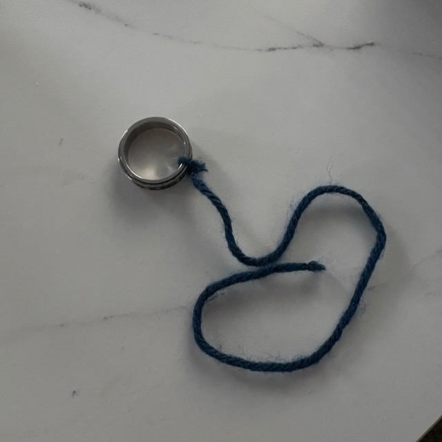 a homemade pendulum; it is a metal ring with yarn tied to it.